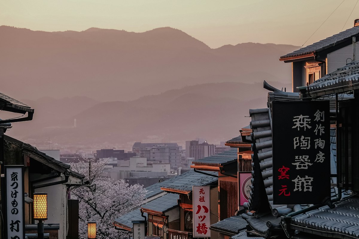 A street lined with cherry blossoms and mountains in the background, Japan